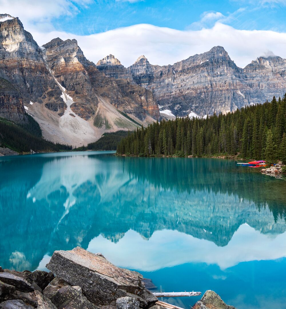 The turquoise waters of Moraine Lake reflecting mountain peaks on a blue bird day in Banff NAtional Park.